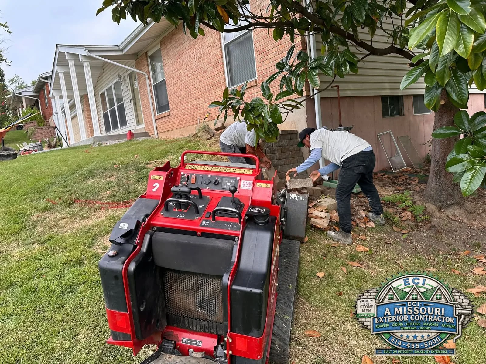 Crew working with block and compact equipment beside a brick home