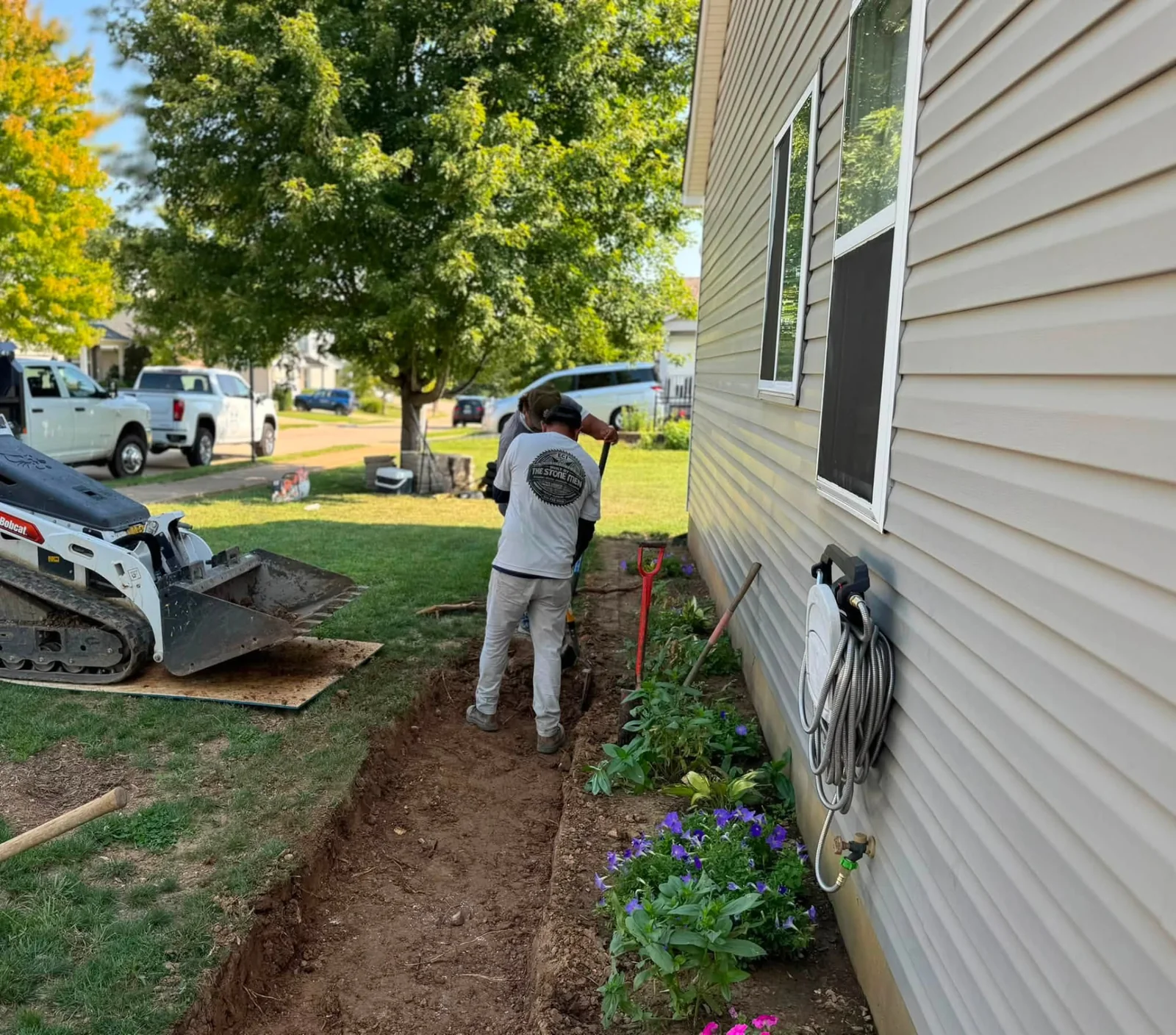 ECI crew member working beside a house during walkway ground preparation