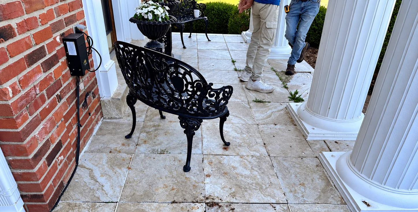 Original worn stone porch surface between white columns and a brick wall