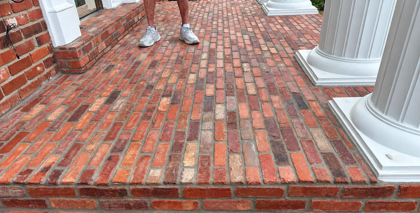 Finished red brick porch surface and steps beside a white column