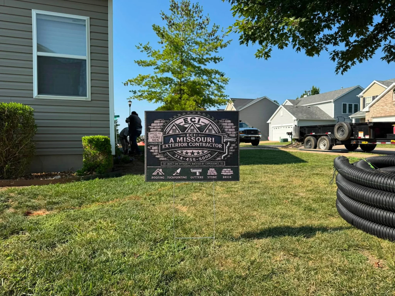 Wide view of an ECI project site with a yard sign, crew and materials
