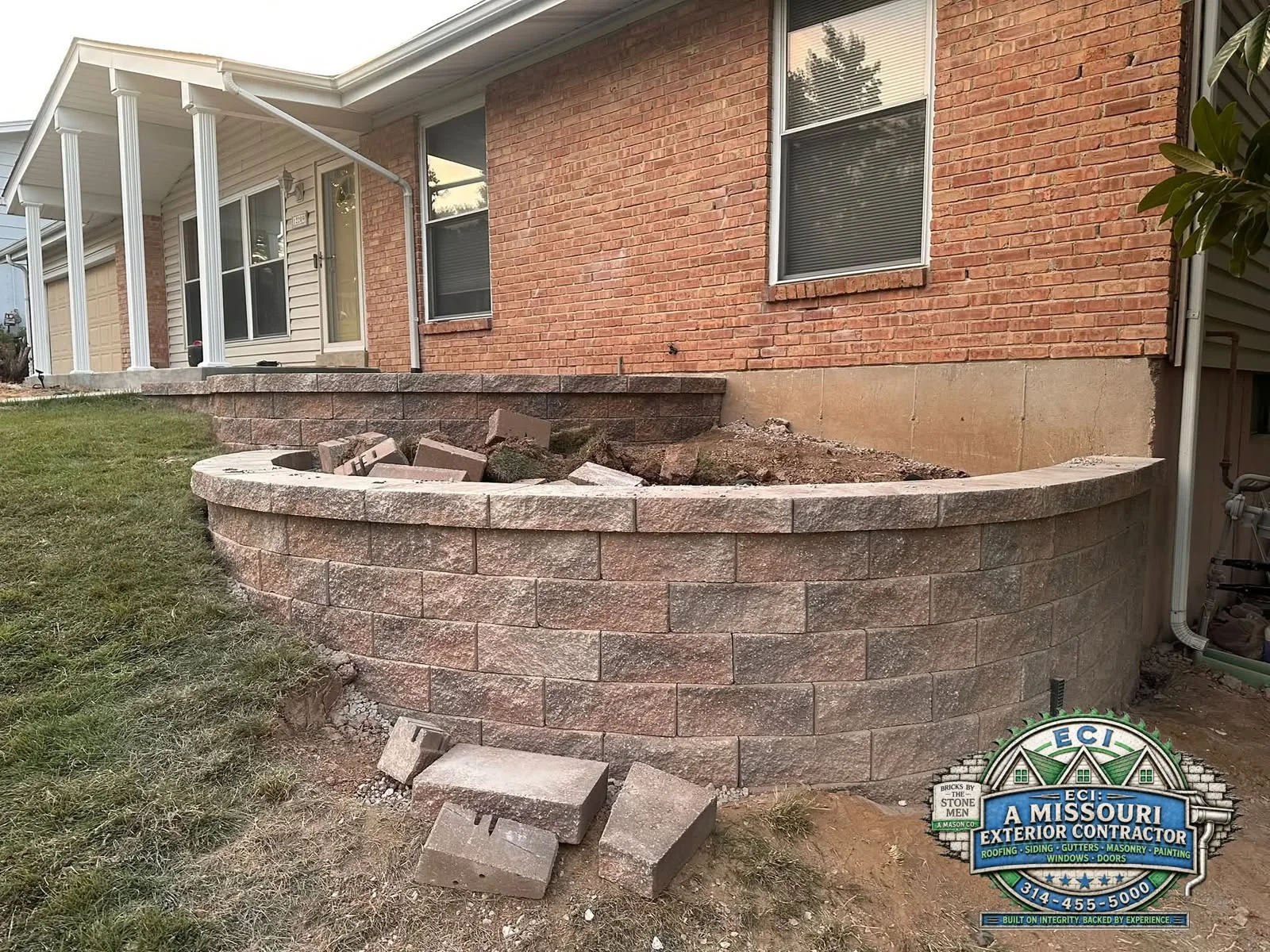 Curved lower section of a block retaining wall with construction materials in front